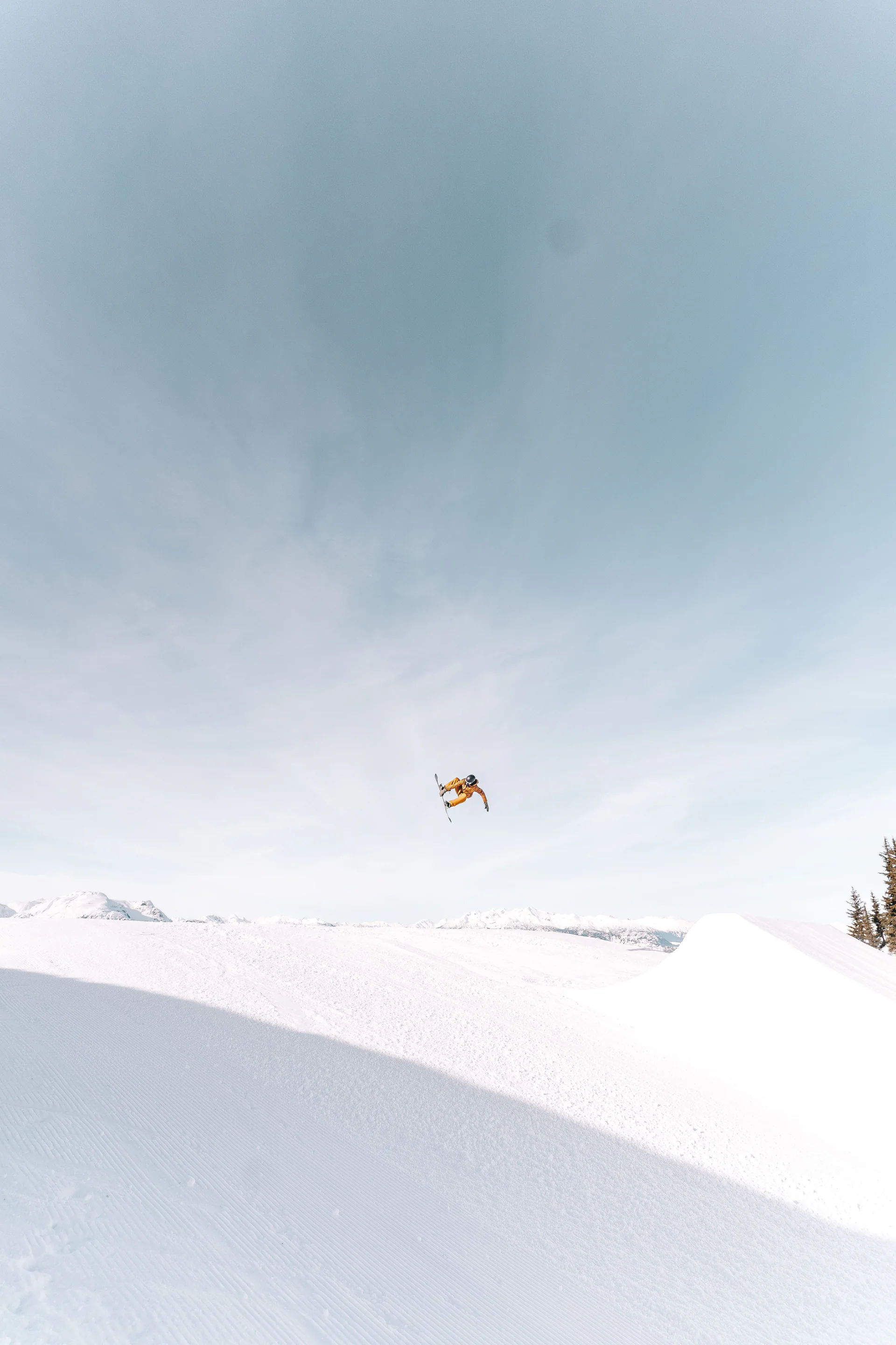 Rider en el aire bajo un cielo amplio en un snowpark.