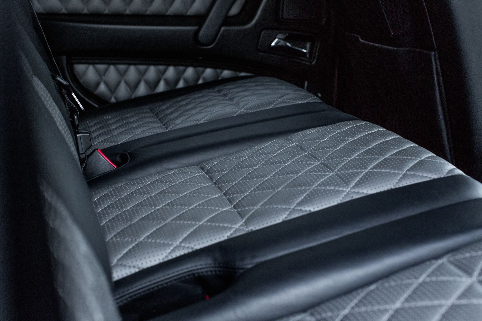 Asiento de cuero gris perforado con costura en rombos, en penumbra